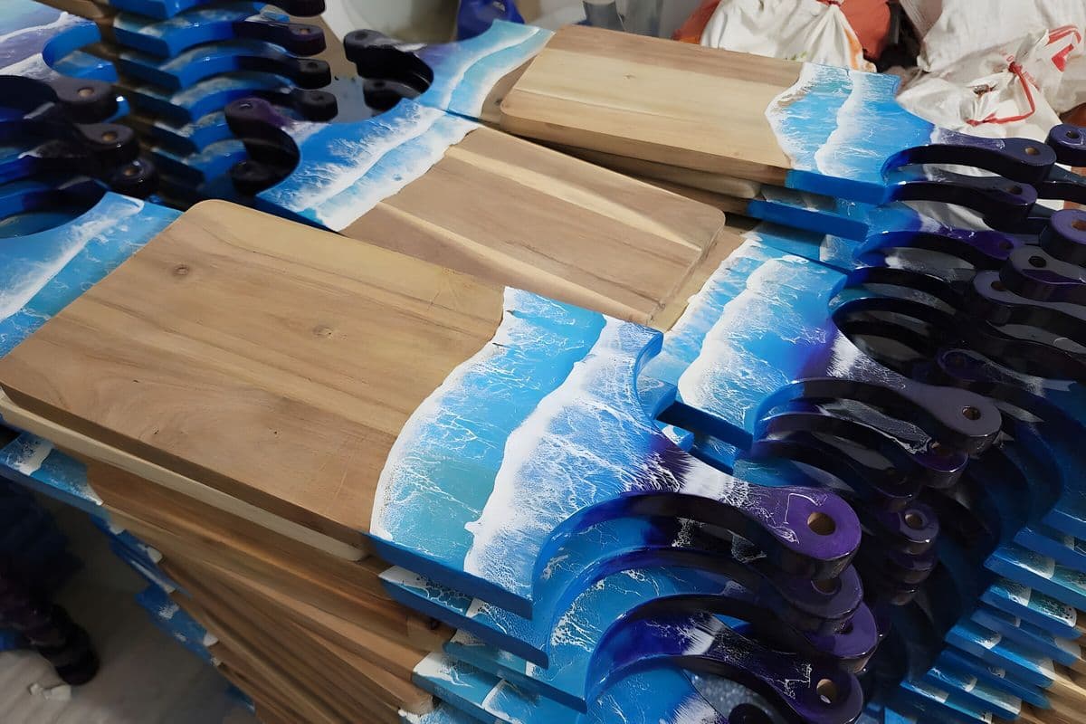 Stacks of acacia serving boards with ocean wave resin handles